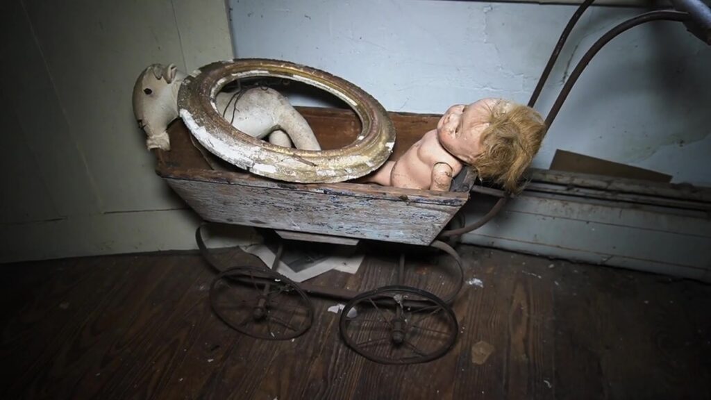 A doll lies in a disused pram in the abandoned property