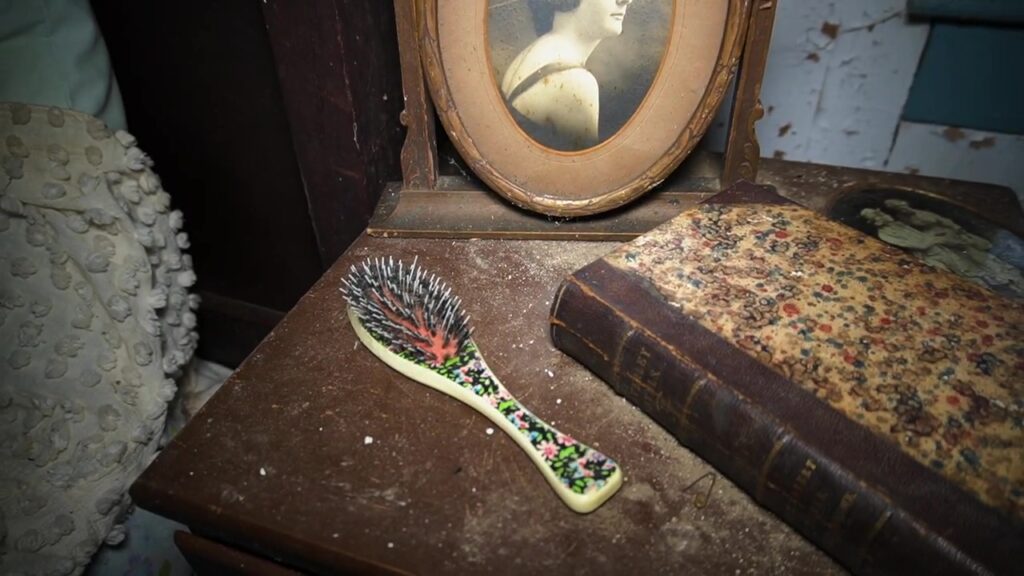 A hairbrush sits on a dressing table, now abandoned 