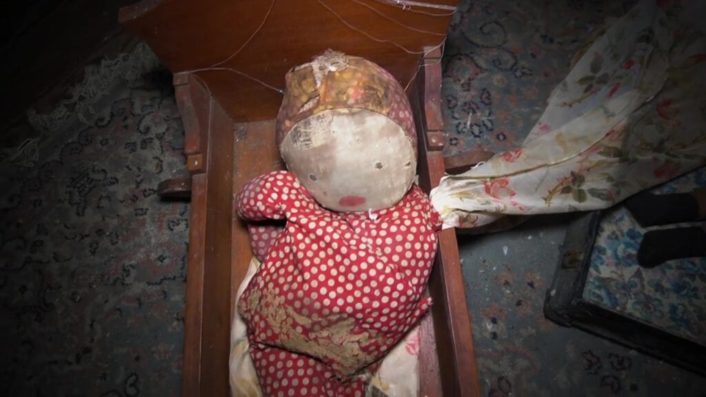 A doll sits in a cradle on the floor of the abandoned property