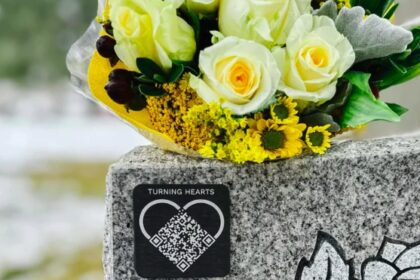 A Turning Hearts QR code medallion attached to a gravestone.