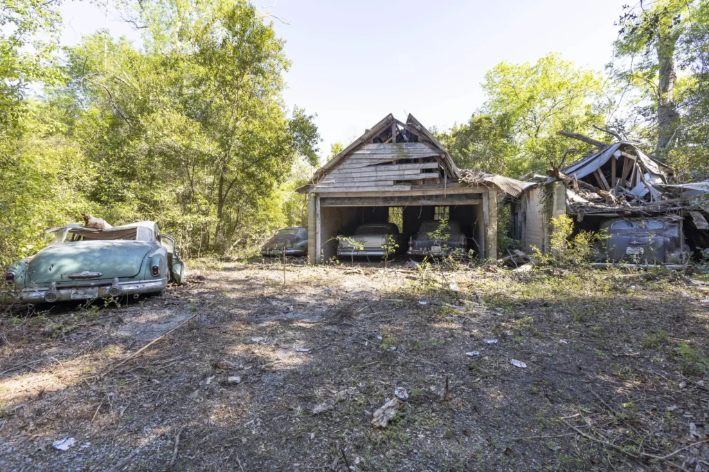 The abandoned property discovered by Urban explorer with vintage cars parked in the garage and driveway.