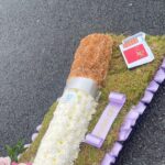 Florist's cheeky cigarette-shaped funeral display with a 'f**k off' ribbon goes viral. Made by Beaukays Bespoke Flowers in Liverpool, it honors a woman who loved cigarettes and telling people off. Social media users joke about similarities to famous smokers like Eastenders' Dot Cotton and Benidorm's Madge Harvey.