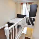 A cramped studio flat in Catford, London, offers a unique layout with a bed crammed onto the landing and a minuscule "lounge" area under the staircase – all for a steep monthly rent of £1,000. Despite its unconventional design, the property boasts a standard-sized kitchen and additional storage space.