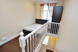 A cramped studio flat in Catford, London, offers a unique layout with a bed crammed onto the landing and a minuscule "lounge" area under the staircase – all for a steep monthly rent of £1,000. Despite its unconventional design, the property boasts a standard-sized kitchen and additional storage space.