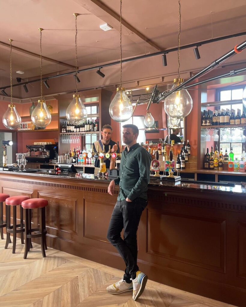 Stuart Broad, retired cricket hero, opens his second pub, The Griffin Inn, in Swithland, Leics. He's seen helping out before the grand opening, owning it with friend Harry Gurney. Fans and locals praise the beautiful decor and wish them success.