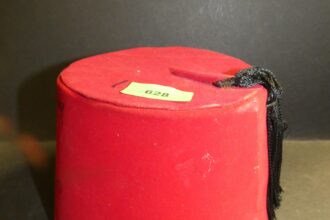 A signed Tommy Cooper fez fetched £62 at auction, sparking a hilarious bidding war reminiscent of the comedian's skits. The auctioneer's quips, including Cooper's catchphrase "Just like that," added to the comedic atmosphere. Cooper's iconic fez, borrowed from a waiter during a Cairo performance, became his trademark, immortalizing his legacy in comedy despite his sudden passing in 1984.