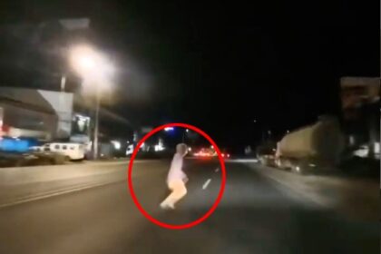 A motorcyclist's helmet camera captures a spooky moment as a small figure appears to dash across the road before vanishing, leaving viewers baffled.