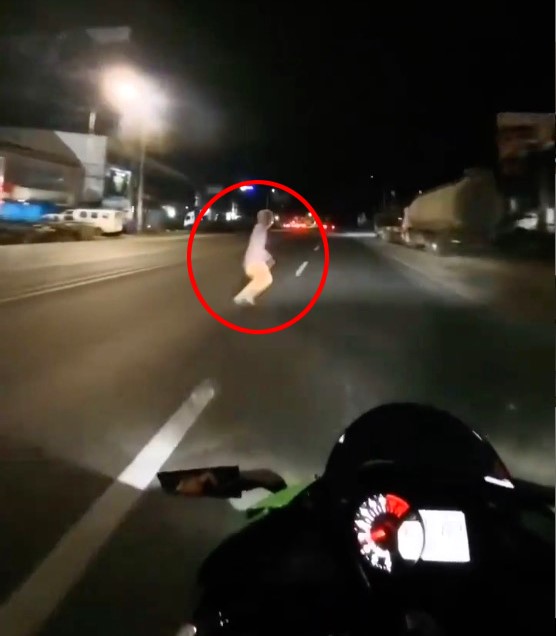 A motorcyclist's helmet camera captures a spooky moment as a small figure appears to dash across the road before vanishing, leaving viewers baffled.