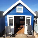 A beach hut in Mudeford Sandbank, Christchurch, Dorset, is up for sale at nearly £440,000, offering stunning coastal views. Despite its lack of facilities like a toilet, the fully furnished cabin sleeps eight and features solar power, a water tank, and a full-size gas cooker.