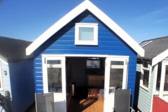 A beach hut in Mudeford Sandbank, Christchurch, Dorset, is up for sale at nearly £440,000, offering stunning coastal views. Despite its lack of facilities like a toilet, the fully furnished cabin sleeps eight and features solar power, a water tank, and a full-size gas cooker.