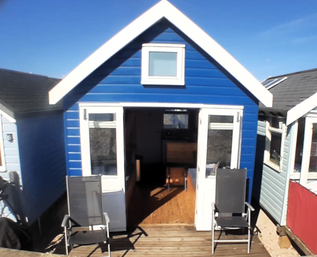 A beach hut in Mudeford Sandbank, Christchurch, Dorset, is up for sale at nearly £440,000, offering stunning coastal views. Despite its lack of facilities like a toilet, the fully furnished cabin sleeps eight and features solar power, a water tank, and a full-size gas cooker.