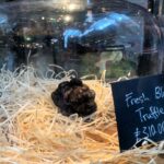 At a London food market, a rare black truffle fetches a hefty price of £310 per 100 grams, leaving shoppers astonished at its luxury.