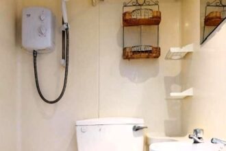 A studio flat in central London, renting for £1,257/month, features a compact space with a single bed, small kitchenette, and an unusual 'en-suite' bathroom where tenants shower next to the toilet.