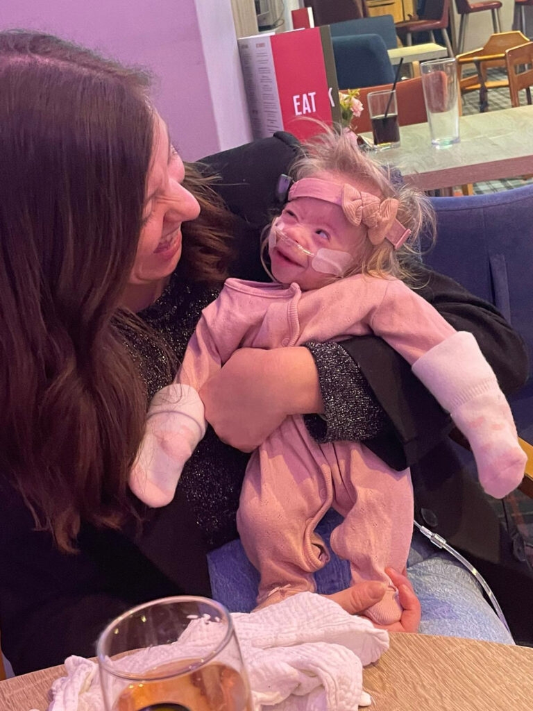 A tiny fighter, Nora, born weighing just 1lb 2oz, battles her rare condition with a contagious smile. Her parents share her feeding tube journey and resilience.