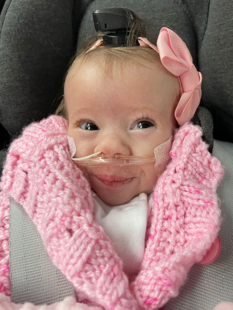 A tiny fighter, Nora, born weighing just 1lb 2oz, battles her rare condition with a contagious smile. Her parents share her feeding tube journey and resilience.