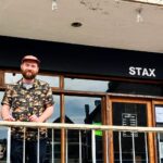 Chef Ben Harrison, former apprentice of Marco Pierre White, opens Stax on Newquay Beach, offering innovative sandwiches inspired by global culinary journeys and a unique blend of food and vinyl music.