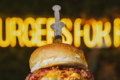 MonkeyFood's new 'Burger Dalsi' in Spain features beef patties, bacon, cheddar, and a syringe with a mixture resembling children's medicine, sparking curiosity and controversy online.