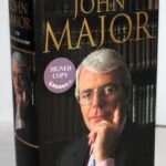 In a charity auction, a signed copy of Sir John Major’s autobiography sells for just £13.50, cheaper than its retail price, marking an unexpected turn.