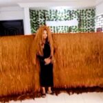 Helen Williams sets a Guinness World Record with an 11 ft 11 in wide wig, crafted from 800 bundles of hair and over 1,000 rhinestones, completed in just over a month.