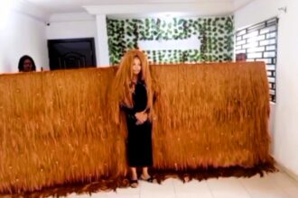 Helen Williams sets a Guinness World Record with an 11 ft 11 in wide wig, crafted from 800 bundles of hair and over 1,000 rhinestones, completed in just over a month.
