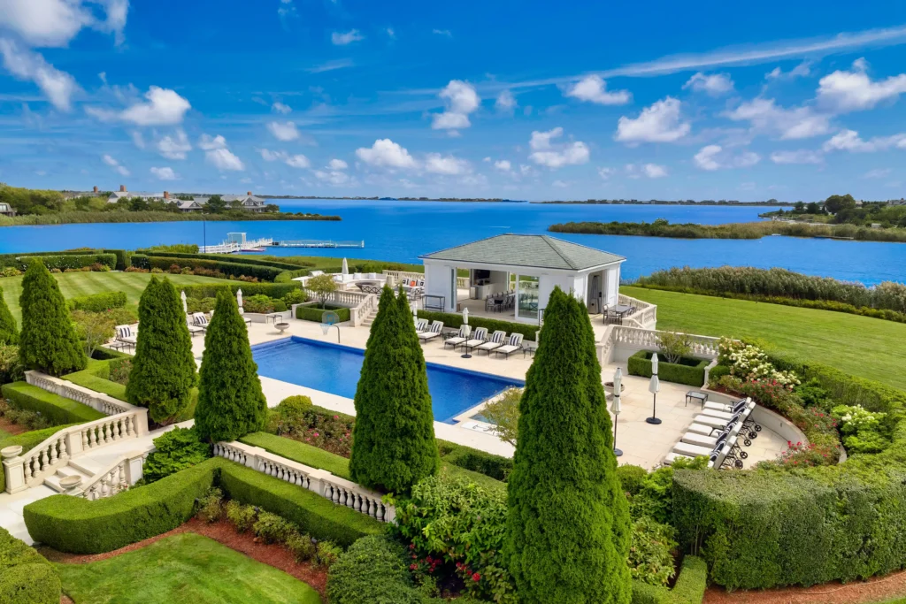 Luxury Hamptons compound with 24 bedrooms, 38 bathrooms, indoor basketball court, and 750-gallon shark tank listed for £77.8m ($99.5M). Stunning ocean views and amenities.