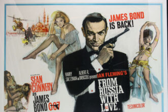 James Bond fans bid on 518 items at a 007 auction, with memorabilia like a From Russia With Love poster fetching £9,100. The auction in Woking raised over £30,000.
