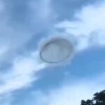 Mysterious 'ring' UFO spotted in broad daylight over Valencia, Venezuela, stuns locals. While some claim it's an alien visit, others suggest it's smoke from industrial sources.