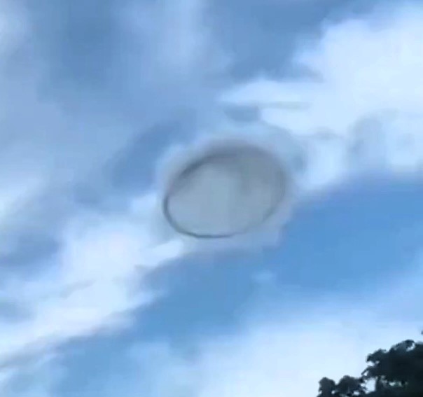 Mysterious 'ring' UFO spotted in broad daylight over Valencia, Venezuela, stuns locals. While some claim it's an alien visit, others suggest it's smoke from industrial sources.