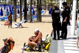 Holiday-goer warns of police clamping down on beach drinking in Benidorm. Viral video shows tourists fined for drinking wine, highlighting strict enforcement.