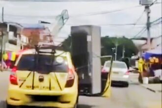 Driver in Medellín, Colombia, spotted transporting a huge fridge and rocking chair strapped to his taxi. Video of the bizarre scene goes viral amid Copa America final.