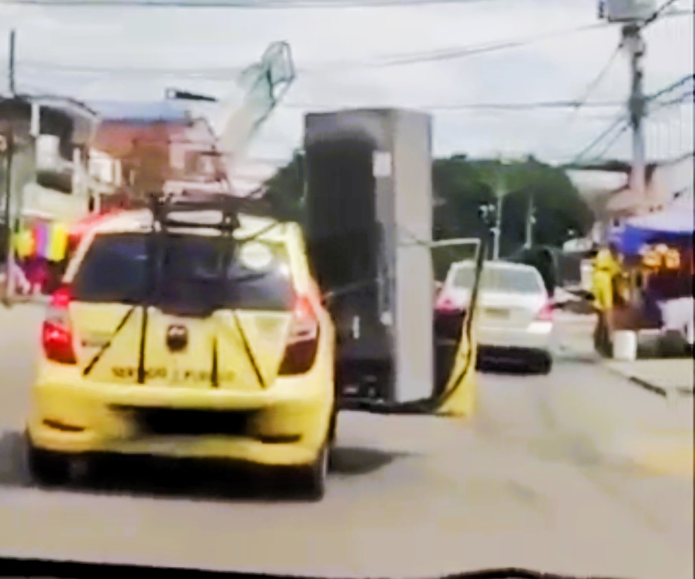 Driver in Medellín, Colombia, spotted transporting a huge fridge and rocking chair strapped to his taxi. Video of the bizarre scene goes viral amid Copa America final.