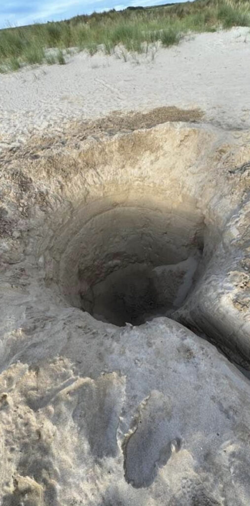 Fears for kids' safety as an 8ft deep hole is found on Tregirls beach, Cornwall. Locals alarmed; HM Coastguard warns of danger. Hole filled by digger to prevent accidents.