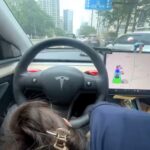 A man filmed himself in a Tesla as a woman appeared to perform a sex act while driving on a busy road in China, sparking outrage. The incident has raised safety concerns.