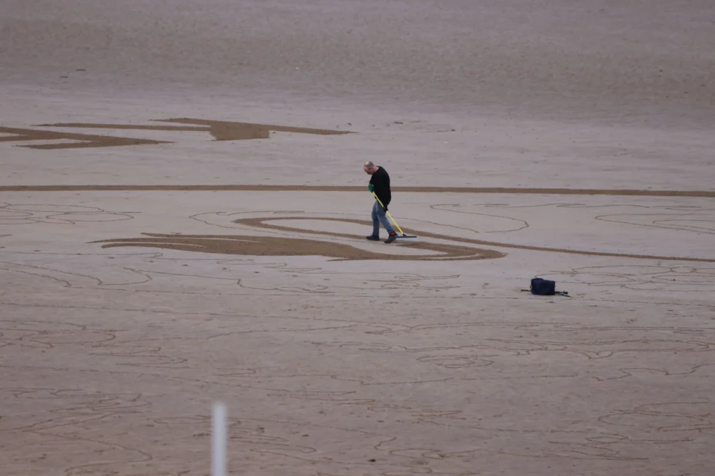 Artist Fred Brown created a huge England football badge on Bridlington beach to inspire Euro 2024 stars, captured by drone before the tide swept it away.