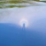 A Brocken spectre, a rare weather phenomenon resembling a shimmering ghost, was spotted in the Cambrian Mountains of Wales, casting an eerie, magnified shadow with a glowing halo.