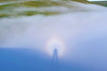 A Brocken spectre, a rare weather phenomenon resembling a shimmering ghost, was spotted in the Cambrian Mountains of Wales, casting an eerie, magnified shadow with a glowing halo.