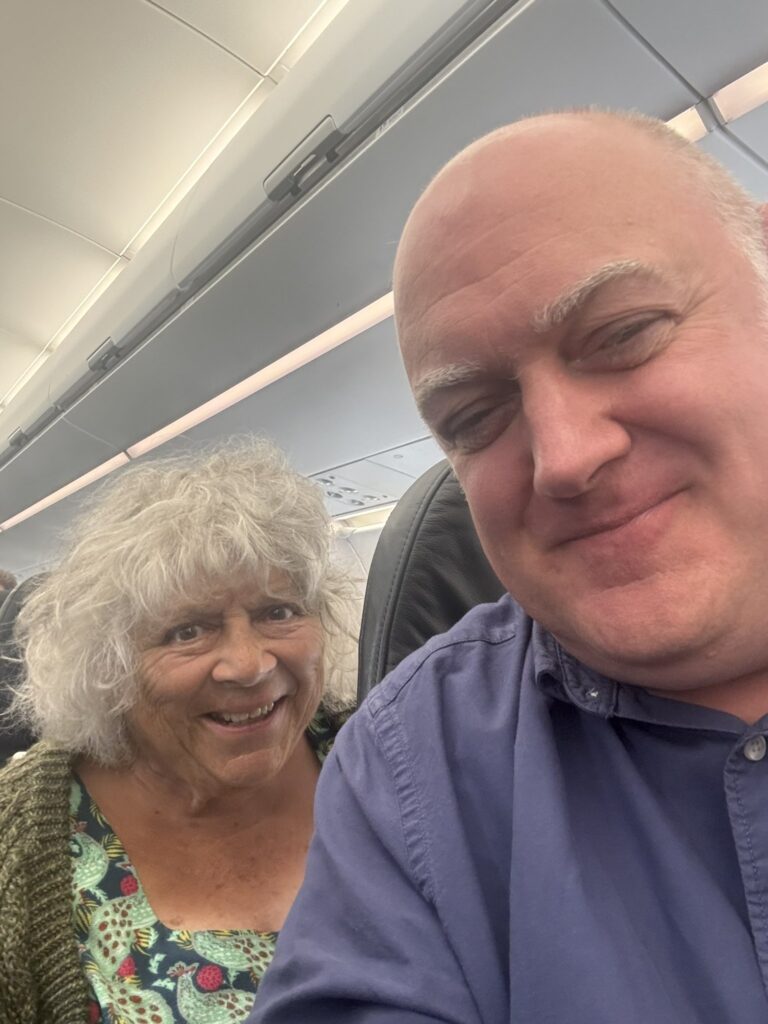 Comedian Dara Ó Briain shares a flight with "national treasure" Miriam Margolyes after Edinburgh Fringe, sparking fan banter about her mischievous charm. A memorable encounter!