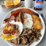 Diehard fry-up fans criticize Billingsgate Cafe's Full English breakfast with scallops, sparking debate over the unique £13 dish featuring traditional items and scallops in garlic butter.