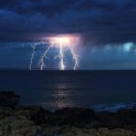 A stunning War of the Worlds-like lightning bolt illuminates the UK coast during the hottest day of the year, captured in an awe-inspiring photo by Stephen Jones.