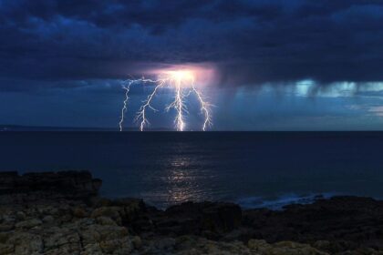 A stunning War of the Worlds-like lightning bolt illuminates the UK coast during the hottest day of the year, captured in an awe-inspiring photo by Stephen Jones.