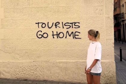 A tourist sparks online debate by sarcastically thanking Barcelona for a "warm welcome" beside a "tourists go home" sign, highlighting tensions over mass tourism in the city.