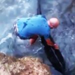 Hero beachgoer Nando saves a dolphin trapped against jagged rocks in Cozze, Italy, on August 3. The viral rescue video shows the dolphin swimming to safety amid cheers.