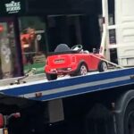 Toy Mini Cooper towed on flatbed in London, sparking jokes about the child owner's 'illegal parking' for sweets. Locals poke fun at the bizarre scene.