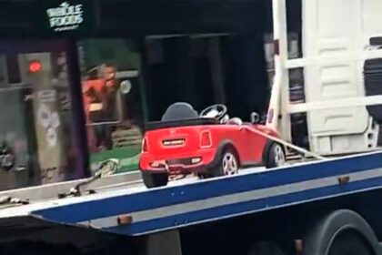 Toy Mini Cooper towed on flatbed in London, sparking jokes about the child owner's 'illegal parking' for sweets. Locals poke fun at the bizarre scene.