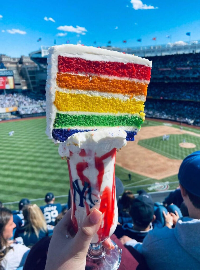 Brits baffled by a £11 gravity-defying freakshake at New York Yankees stadium, featuring a slab of cake on top. Fans question how to eat it and its health impact.