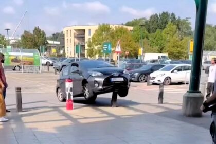 Shoppers stunned as a driver maroons their Toyota Yaris on a bollard outside Morrisons, with spinning wheels and failed attempts to reverse off. Baffled reactions follow.