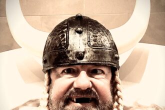 Ricky Gervais gets a cheeky surprise at his Copenhagen hotel: a Viking helmet left with a playful note. Fans urge him to recreate his iconic bath selfie with the gift.