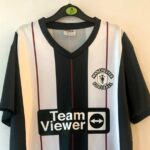 Fake Man United 2023/24 away shirt with a 'Manchester Football' crest and cartoon-like devil mocked by fans. Priced at £15, it's drawing laughs for its comical design.