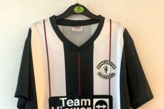 Fake Man United 2023/24 away shirt with a 'Manchester Football' crest and cartoon-like devil mocked by fans. Priced at £15, it's drawing laughs for its comical design.