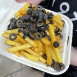 Vegan's bizarre takeaway combo of chips topped with olives shocks social media. Is it genius or gross? See the viral reaction to this unusual Manchester dish!